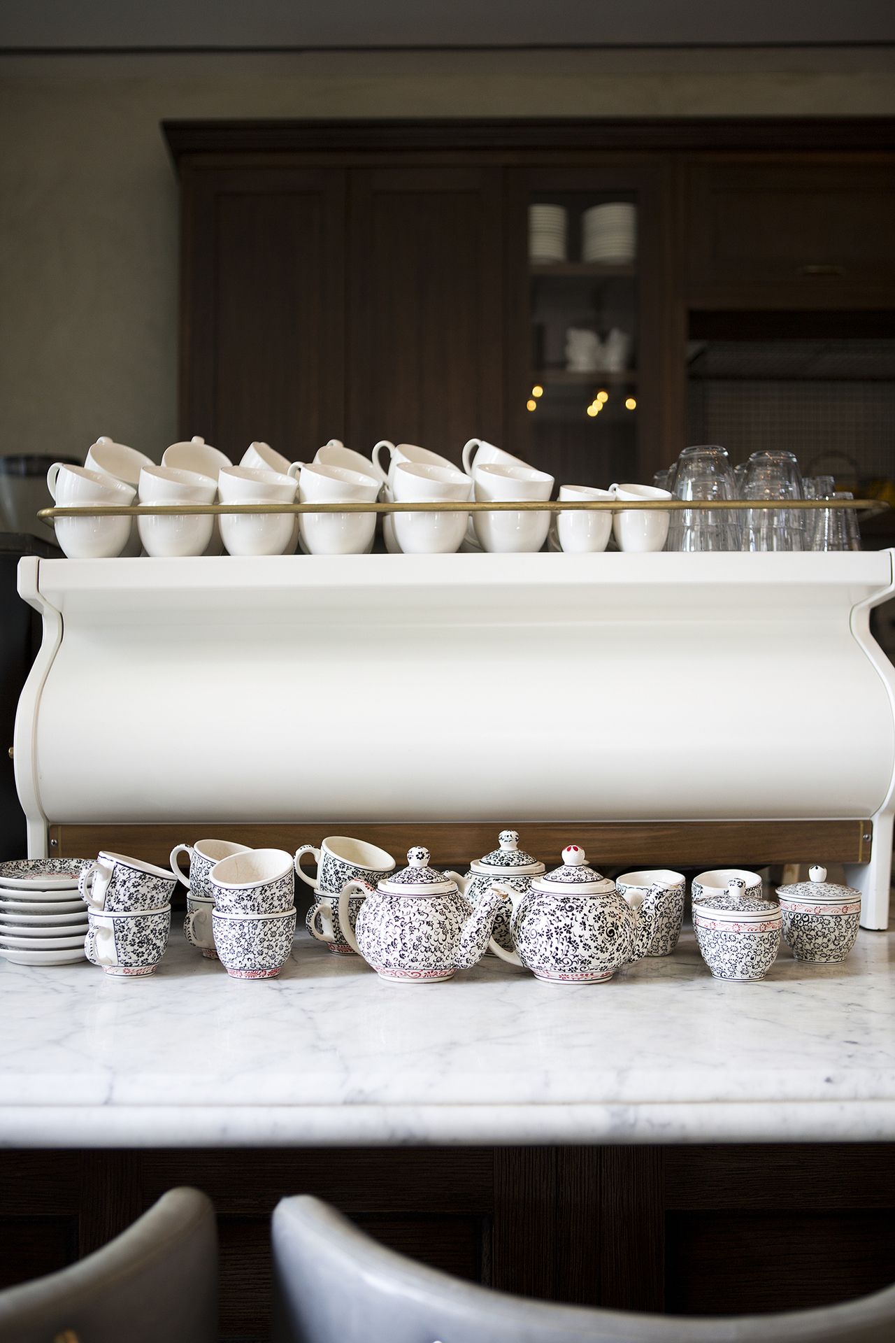 A coffee machine with stacks of patterned teacups